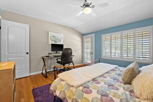 A well-curated bedroom boasting a bed, a functional desk, and a view-framing window.