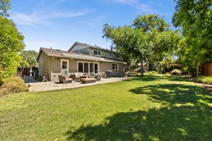 A serene backyard with a lush lawn and an inviting patio.