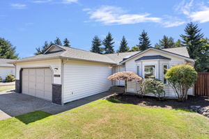 Driveway approach to the generous two-car garage, framed by established greenery and low-maintenance vinyl siding.