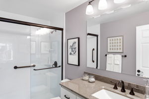 Refreshed ¾ bath with sleek vanity, quartz-style counters, and an easy-step shower with clear glass doors and dual grab bars.
