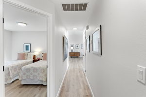 Bright hallway connects the bedrooms to the main living space, with a peek into the charming secondary bedroom.