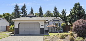 Wide front yard view showcasing mature plantings, fresh mulch, and the home’s inviting single-level design.