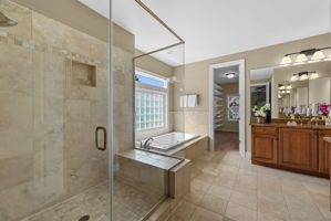 The Primary bathroom is beautifully designed with an oversized glass-enclosed shower, spa tub, private room for the commode, and dual vanities.