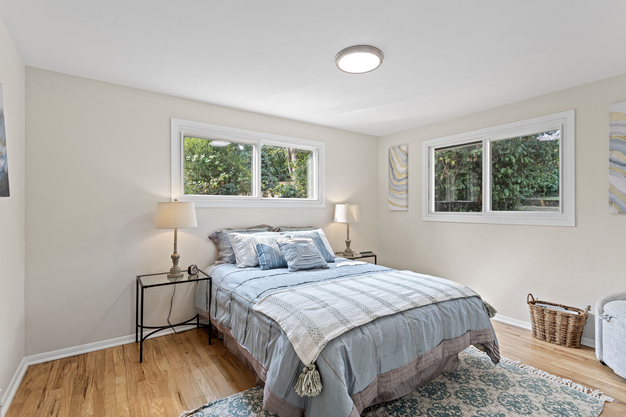 The south bedroom offers extra space and all-day light from its sunny corner windows, plus refinished hardwoods, new lighting, and updated closet doors.