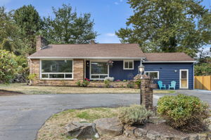 Classic mid-century charm with sandstone planter beds, layered textures, and vinyl windows with future upgrade potential.
