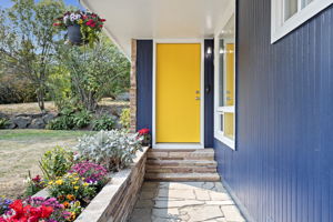 Covered flagstone walkway with classic sandstone and cheerful blooms—an inviting approach that sets the tone for home.