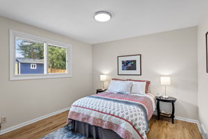 North bedroom overlooks the backyard with a wide western view—sunlight all afternoon and newly refinished oak floors underfoot.