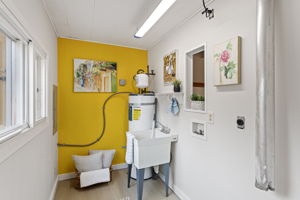 Tucked off the flex room, the dedicated laundry area features cheerful light, a utility sink, and hookups for a side-by-side washer and dryer. A sunny window brightens the chore zone, while a bold pop of color adds personality and warmth.