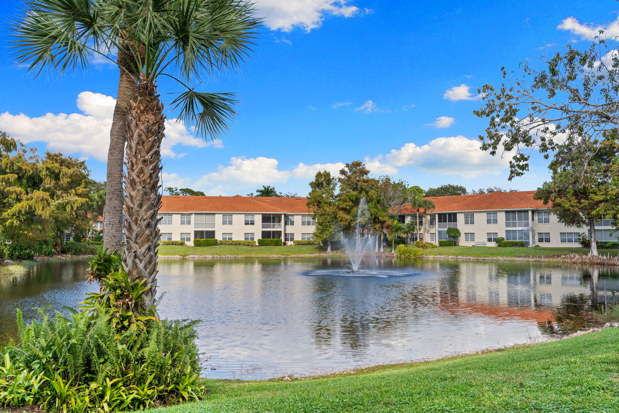 Scenic lake with fountain surrounded by lush landscaping.