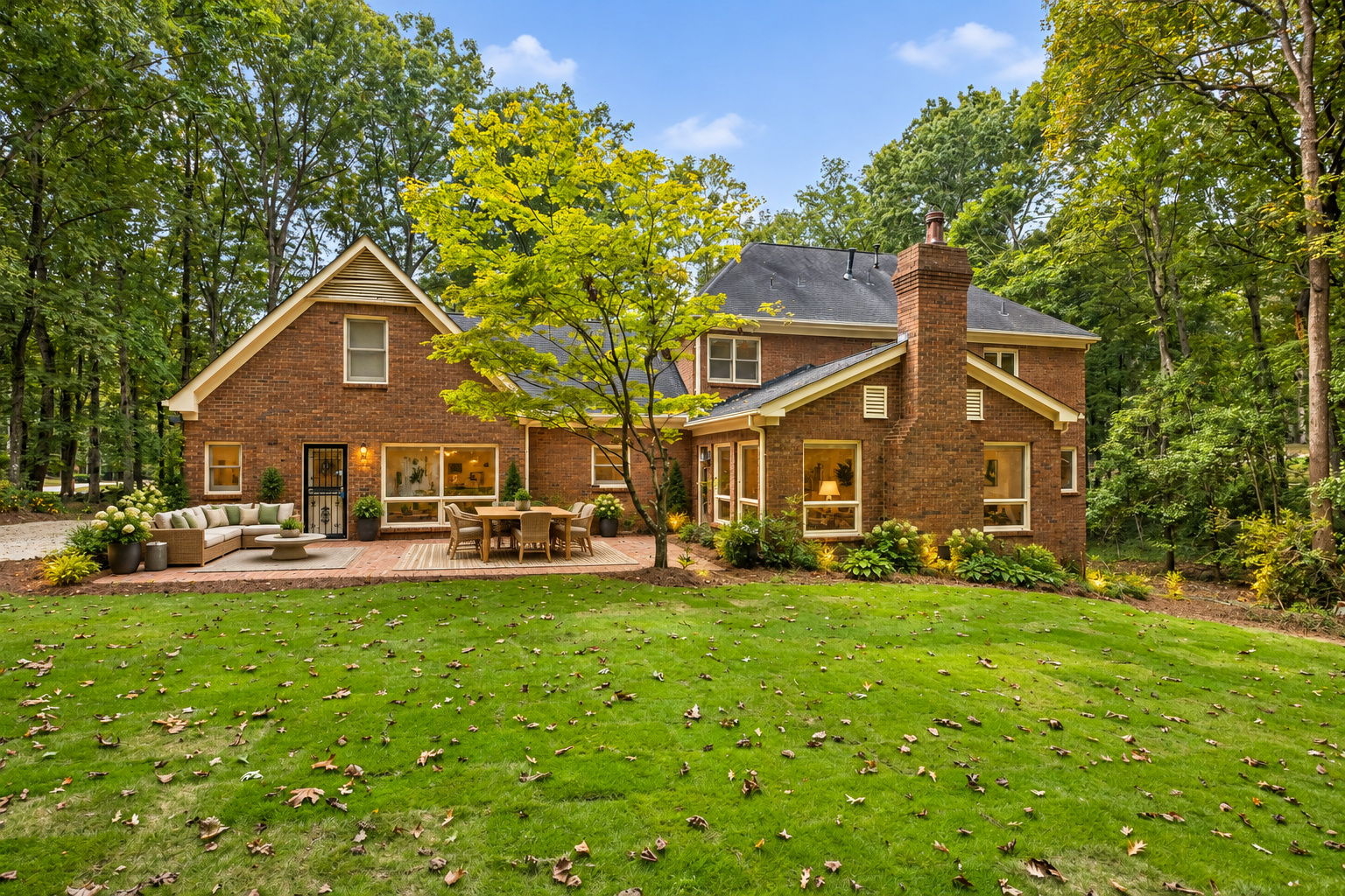 AI Staged - Two-story red brick exterior featuring a multi-gable roofline, exterior brick chimney, Brick patio and new sod