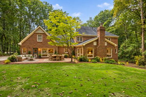 AI Staged - Two-story red brick exterior featuring a multi-gable roofline, exterior brick chimney, Brick patio and new sod