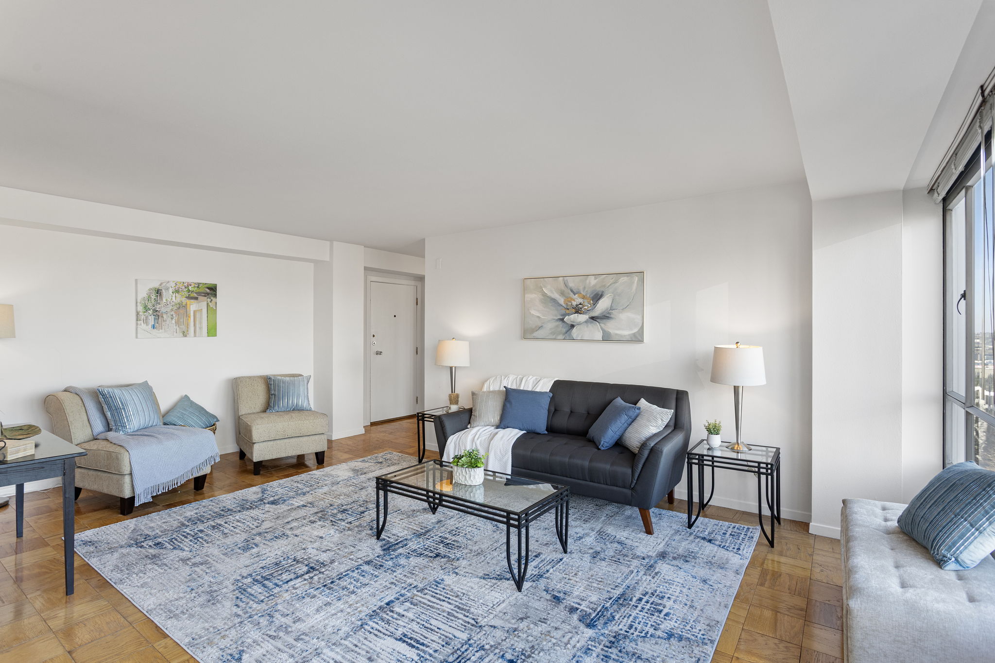 A calm, open living room with an easy line to the bedroom and bath—simple flow, generous wall space, and warm original wood floors.