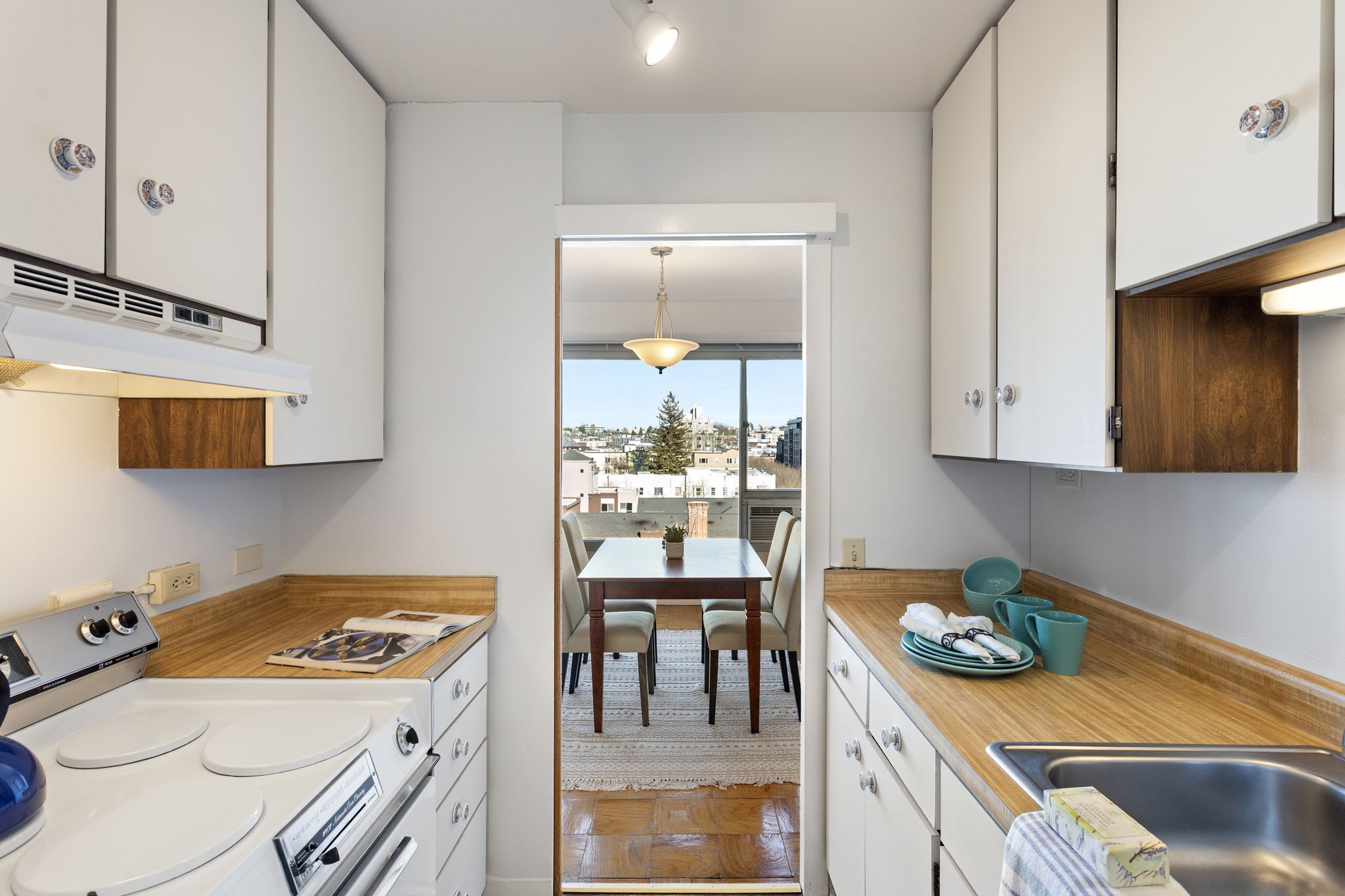 Compact and efficient, this galley kitchen keeps everything close—clean mid-century cabinetry, warm counters, and plenty of storage for everyday cooking.