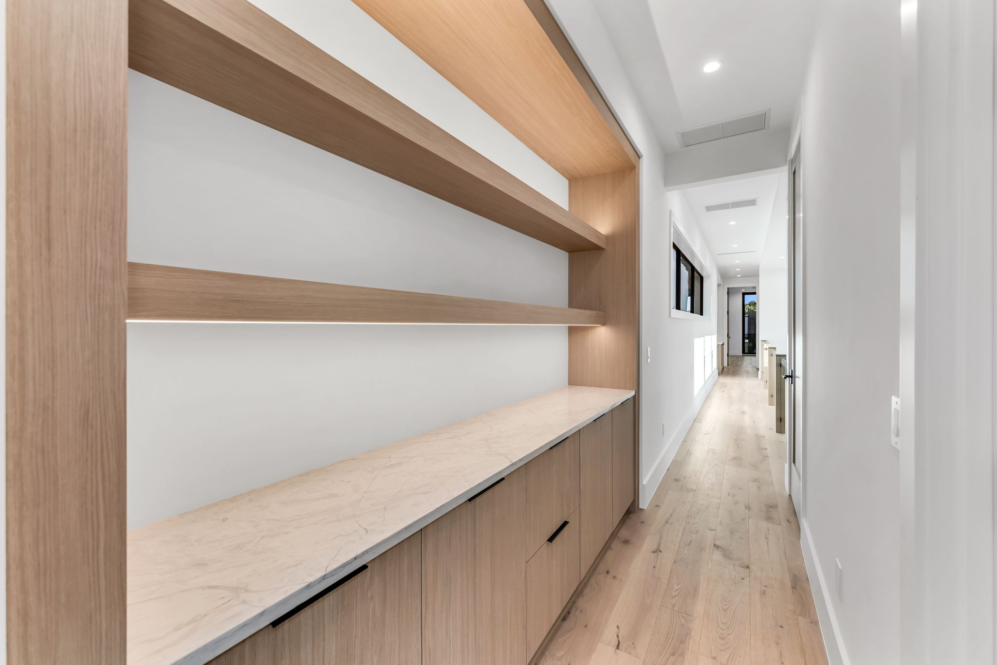 Hallway featuring a built-in bookshelf and coffee bar leading to the upstairs primary suite.