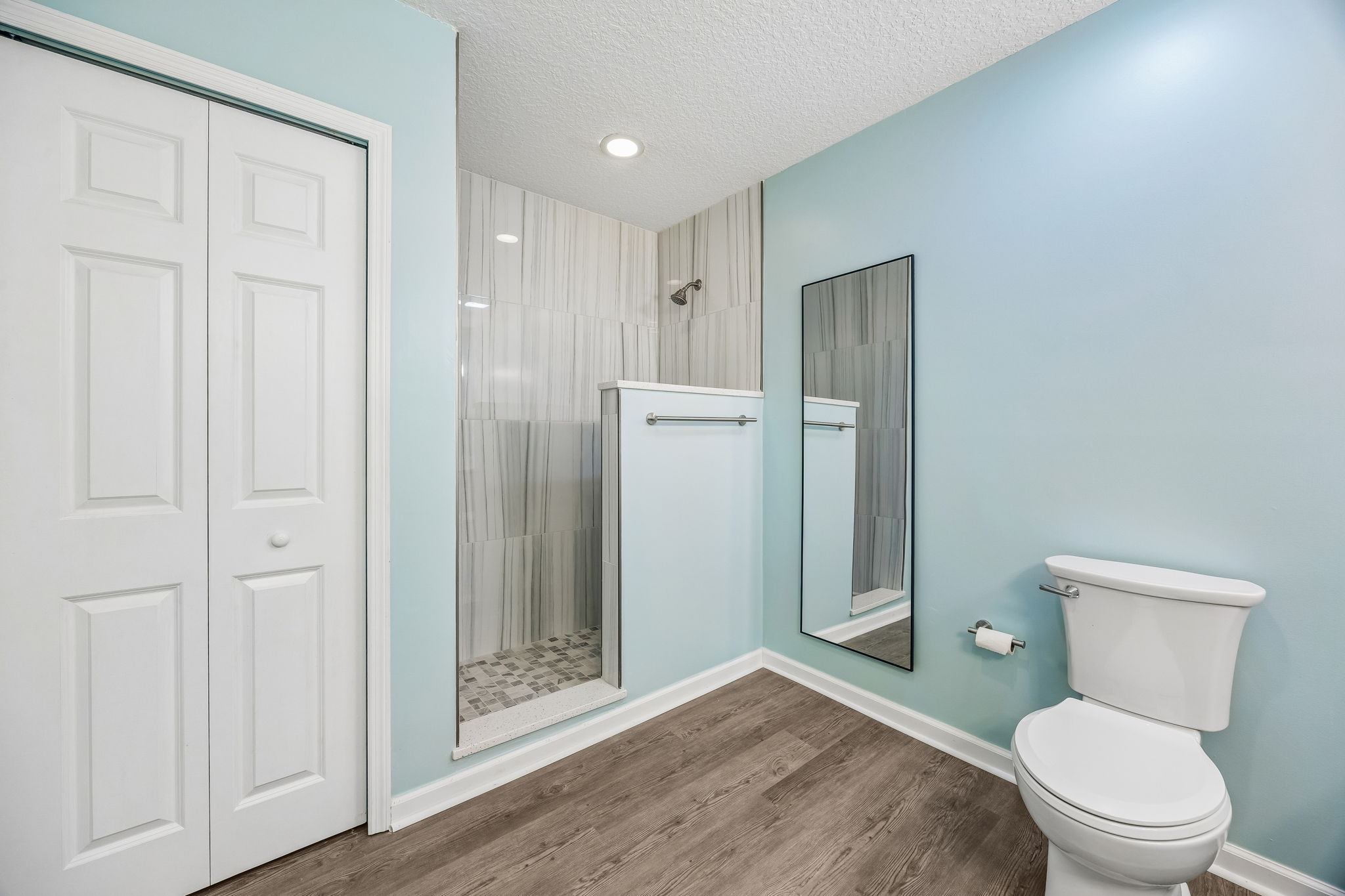 A tiled walk-in shower adds a clean, modern finish, with nearby closet storage completing the layout