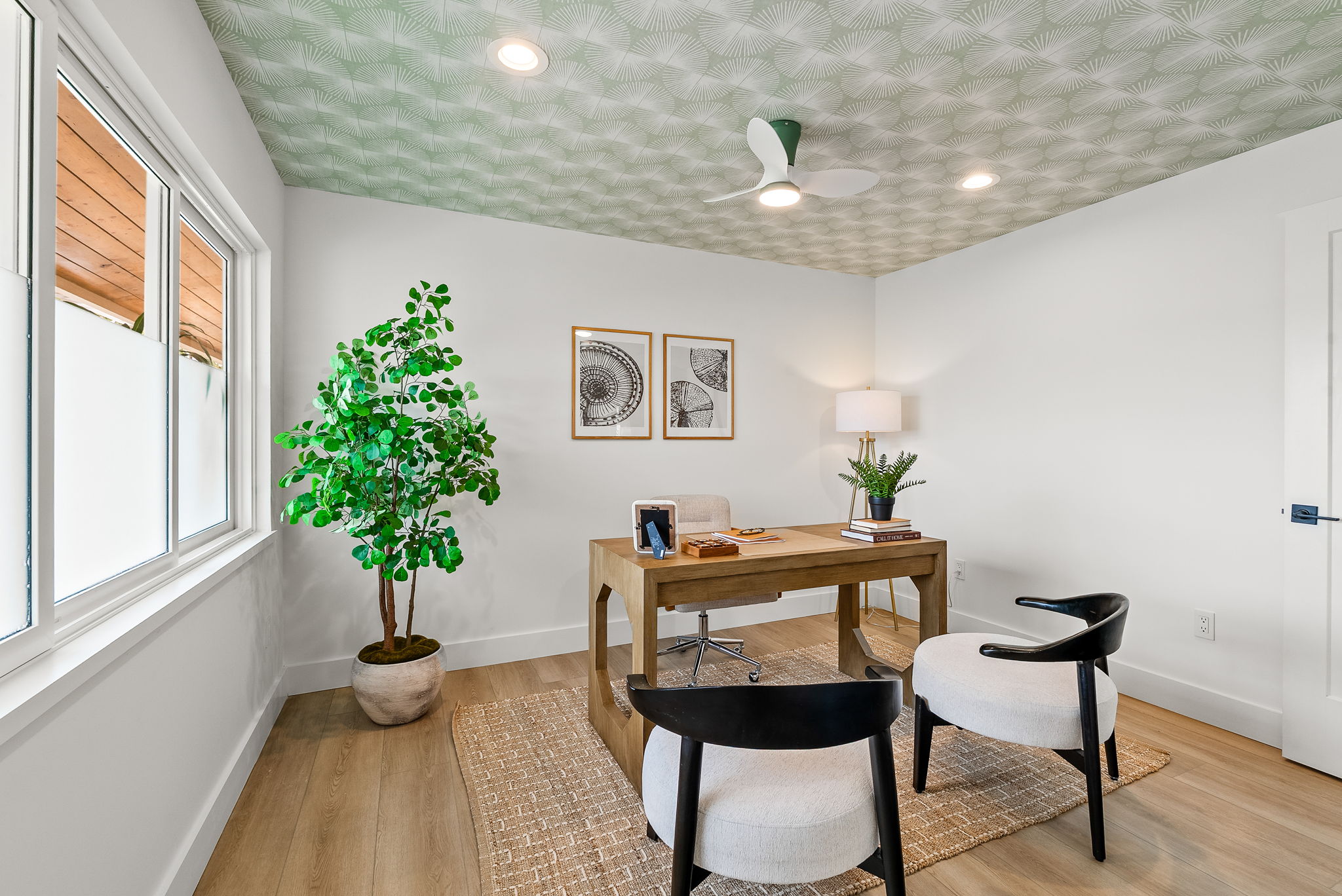 The first of four bedrooms in the main home gets plenty of natural light, perfect for a home office. The patterned ceiling covering elevates the space.