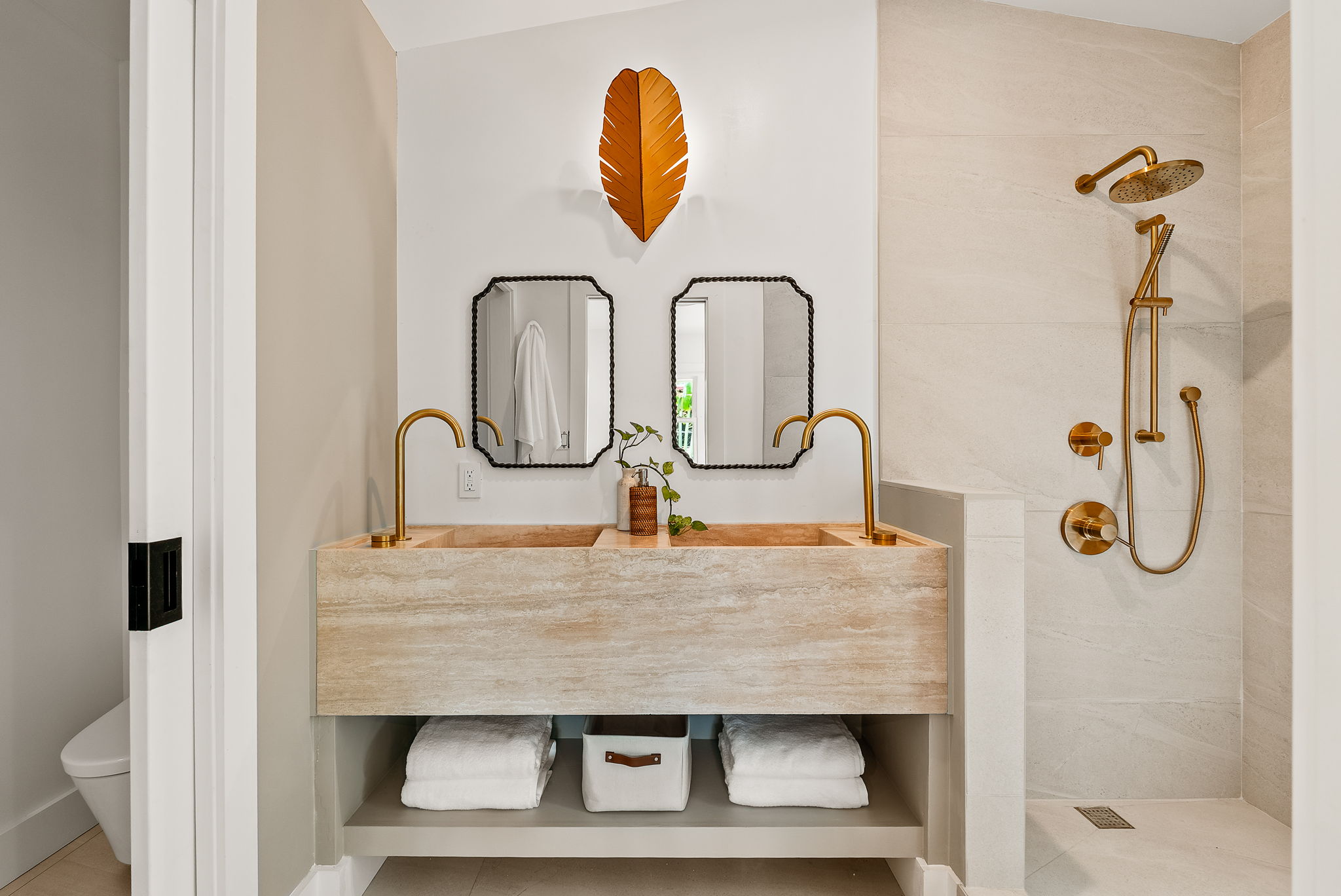 The primary bath vanity is a work of art - cut from a single piece of travertine, this dual vanity is made completely of natural stone. Not shown here - the back wall will be adorned with a custom cut mirror with a leaf-shaped metal light fixture, fitting for this nature inspired home