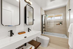 The first of three main residence baths features a tub, trough sink with dual faucets and designer fixtures throughout.