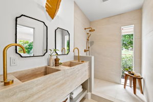 The primary bath vanity is a work of art - cut from a single piece of travertine, this dual vanity is made completely of natural stone. Not shown here - the back wall will be adorned with a custom cut mirror with a leaf-shaped metal light fixture, fitting for this nature inspired home.
