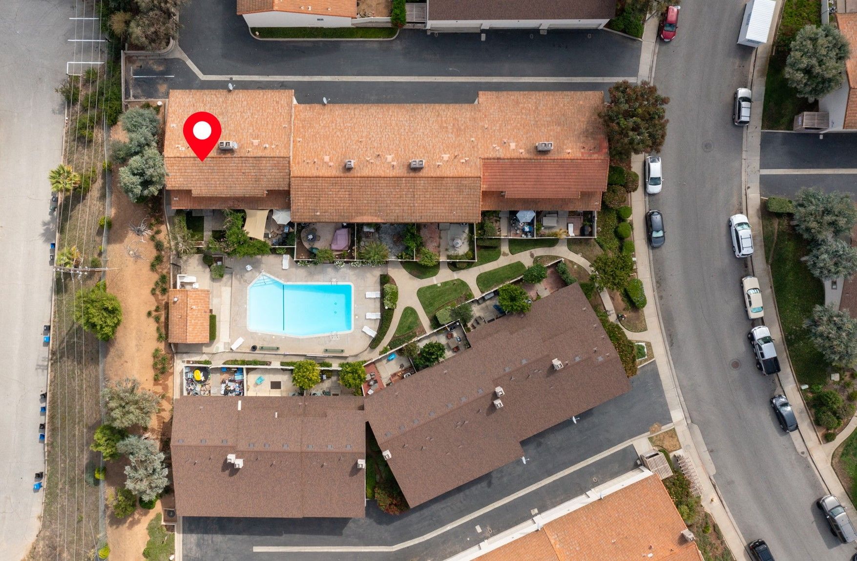Aerial view of unit & fenced private front yard showing proximity to gated & somewhat secluded community pool (1 of multiple pools) located just outside unit's front gate.