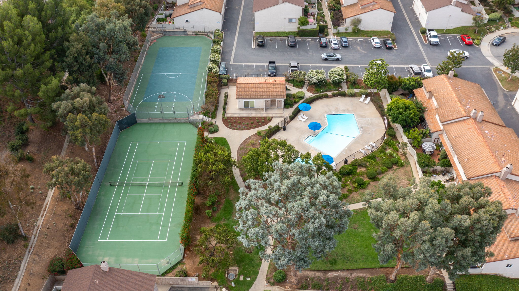 Aerial view of community's main pool/spa area, clubhouse, tennis court, basketball/sport court