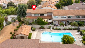 Aerial view of unit & fenced private front yard showing proximity to gated & somewhat secluded community pool (1 of multiple pools) located just outside unit's front gate.