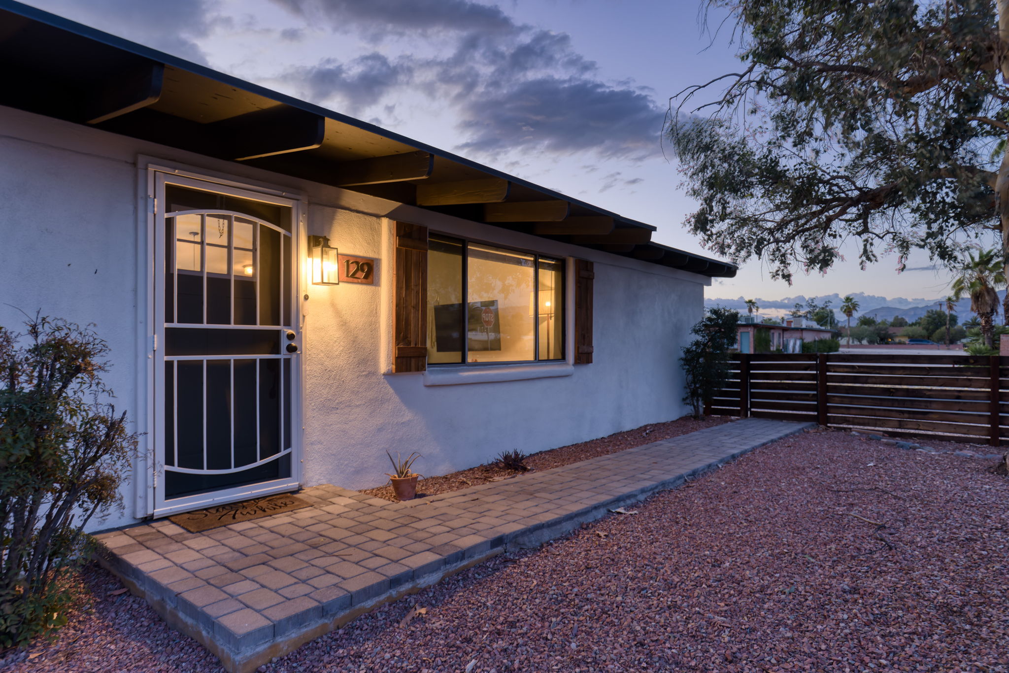 Wood fence, fully enclosed front yard with decorative gravel, mature trees, bushes and river rock.