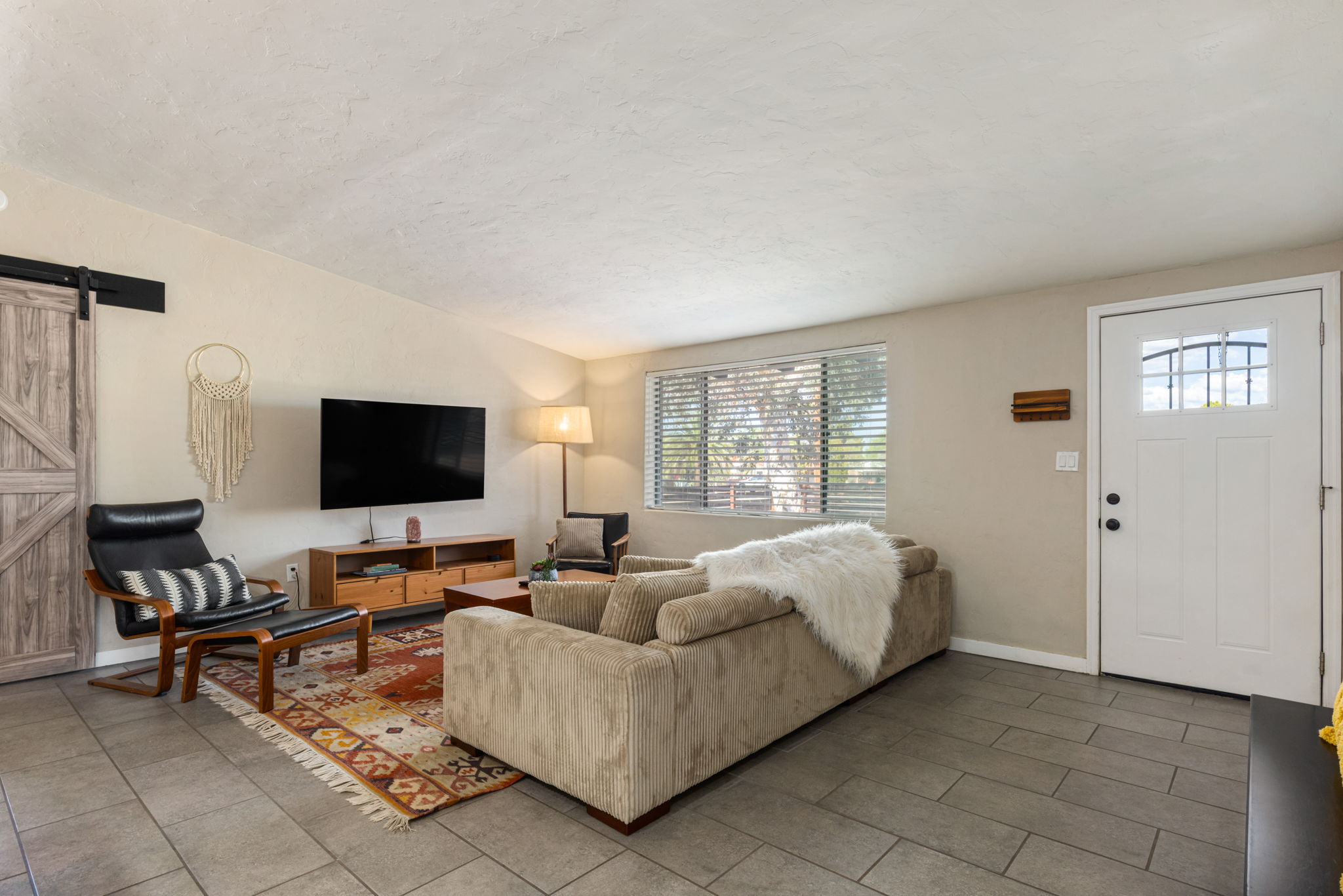 Spacious living area with neutral ceramic tile throughout the living space.