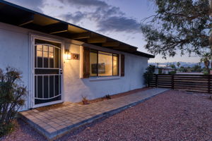 Wood fence, fully enclosed front yard with decorative gravel, mature trees, bushes and river rock.