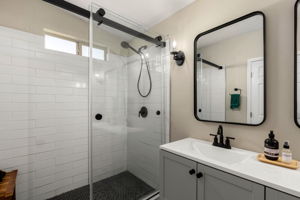 Tile walk in shower with glass sliding door.
