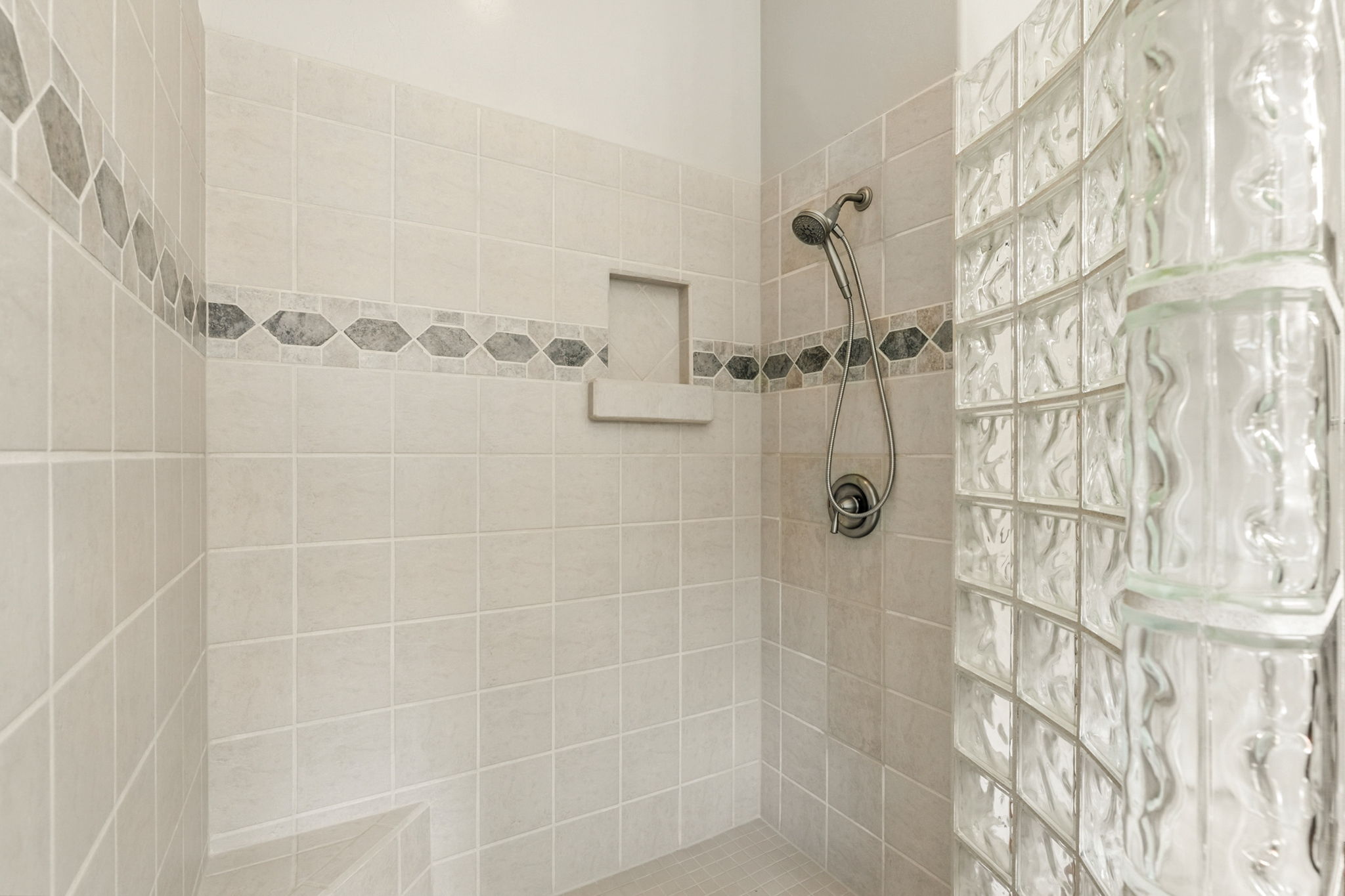 Spacious walk-in shower with glass-block enclosure and corner seat