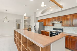 The kitchen features cherry cabinets, corian countertops, and a custom hand painted  backsplash