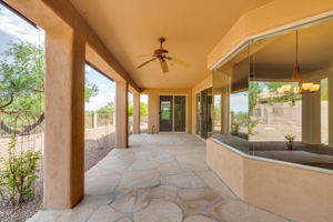 Expansive covered patio featuring flagstone floor and motorized shades