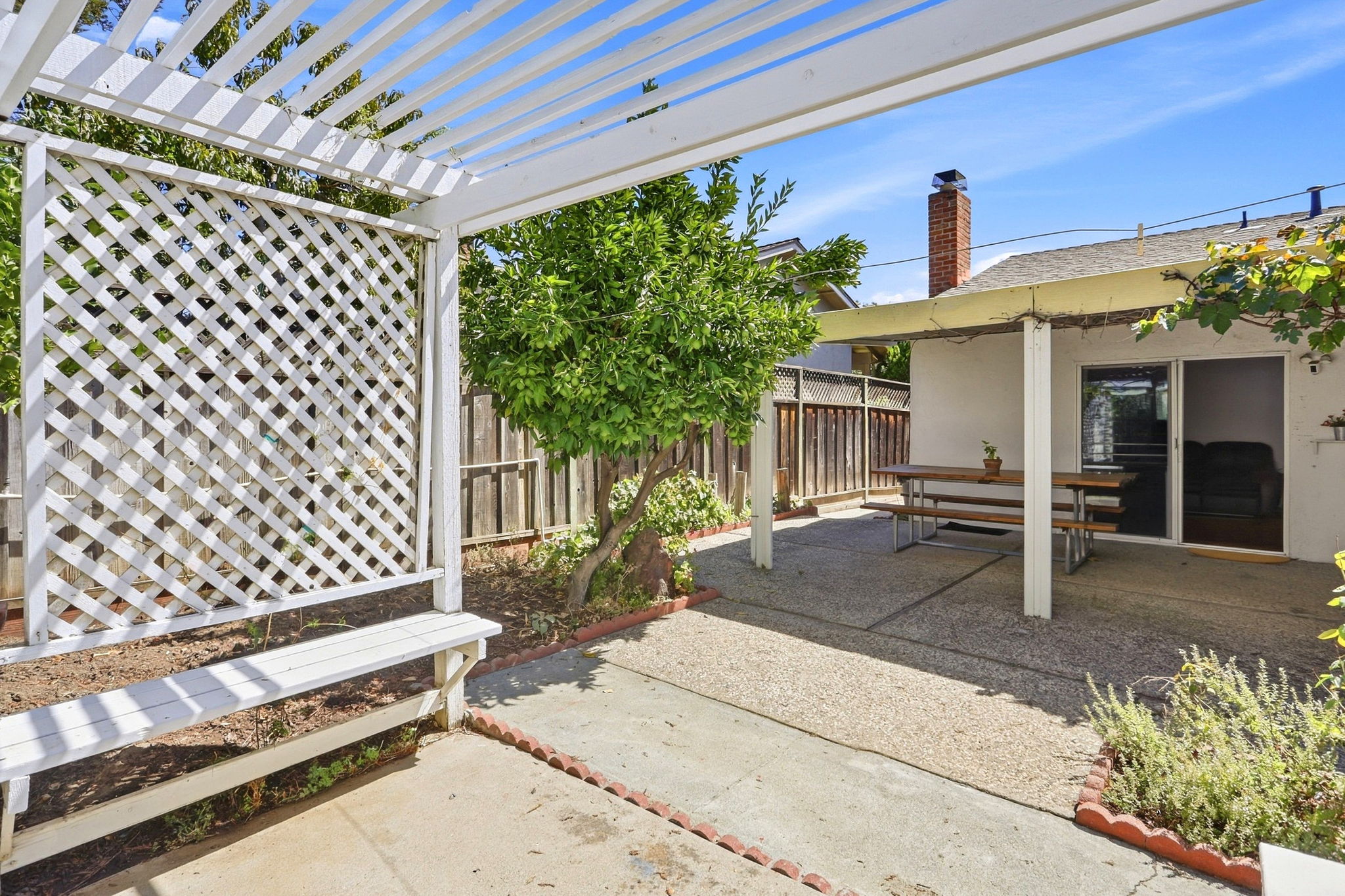 Backyard View of Covered Patio from RT side of Pergola w/path to Garage Side Door w/Laundry area