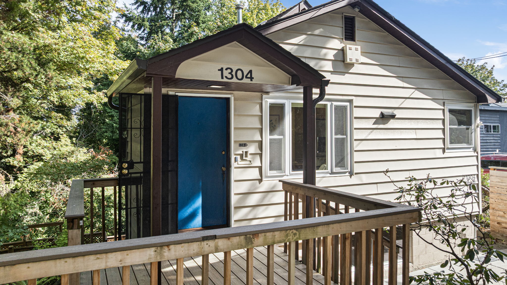 The upper-level unit enjoys a private, elevated entry—tucked behind trees, with a sunny front porch overlooking the street.