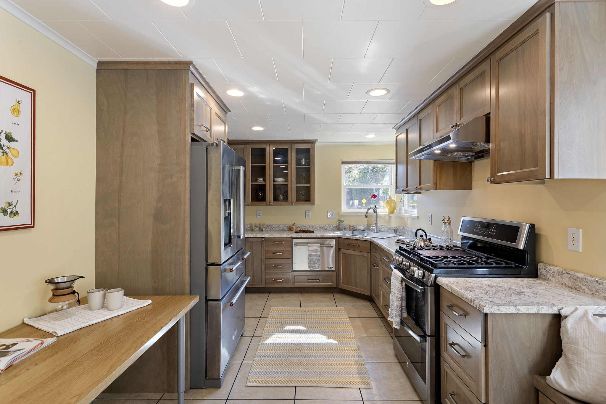U-shaped for efficiency and framed by soft archways, the kitchen features Formica counters, stainless appliances, tile flooring, and custom cabinetry.