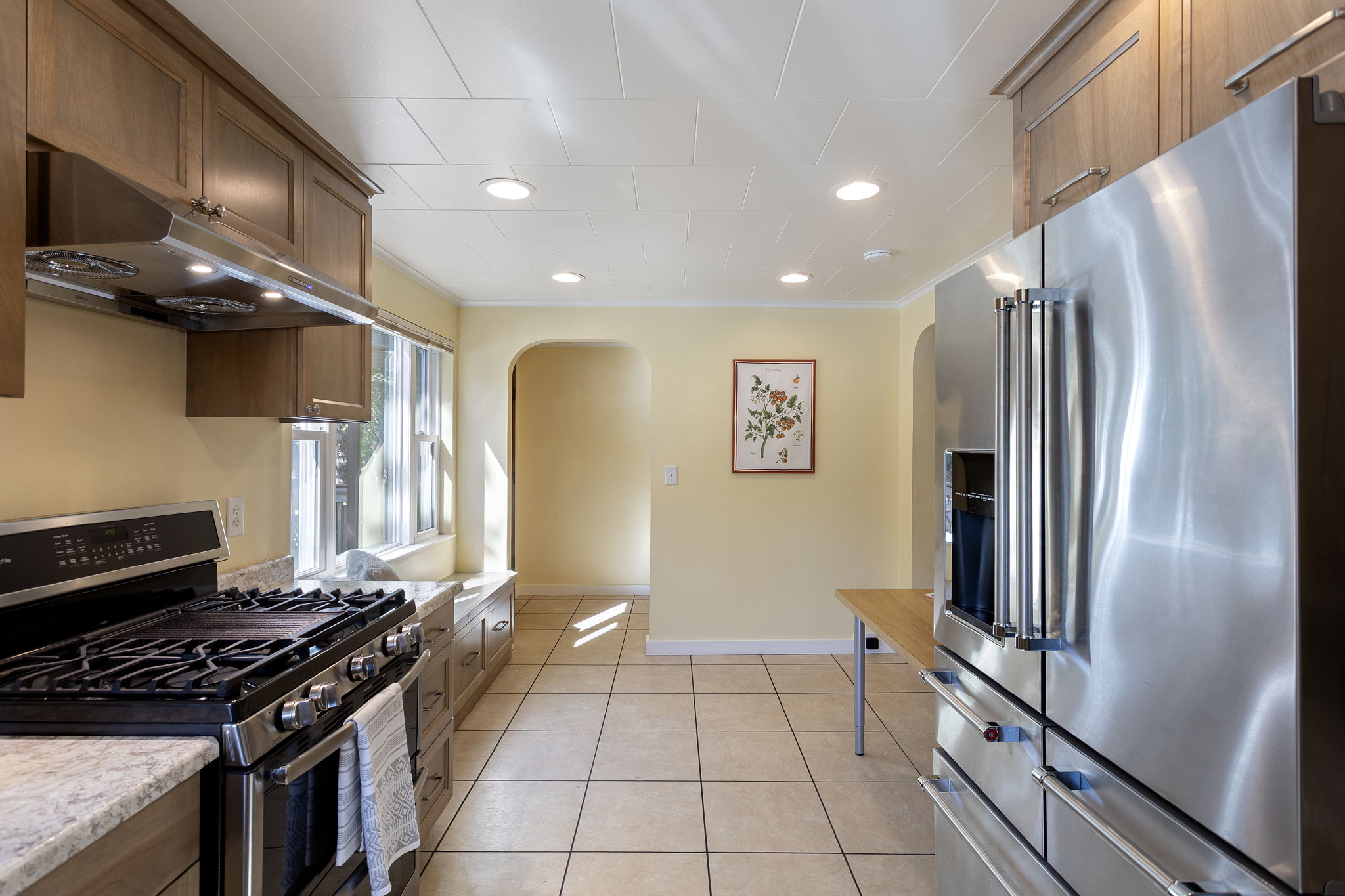 A view back toward the entry highlights tile floors, recessed lighting, and the welcoming layout of the upper unit.