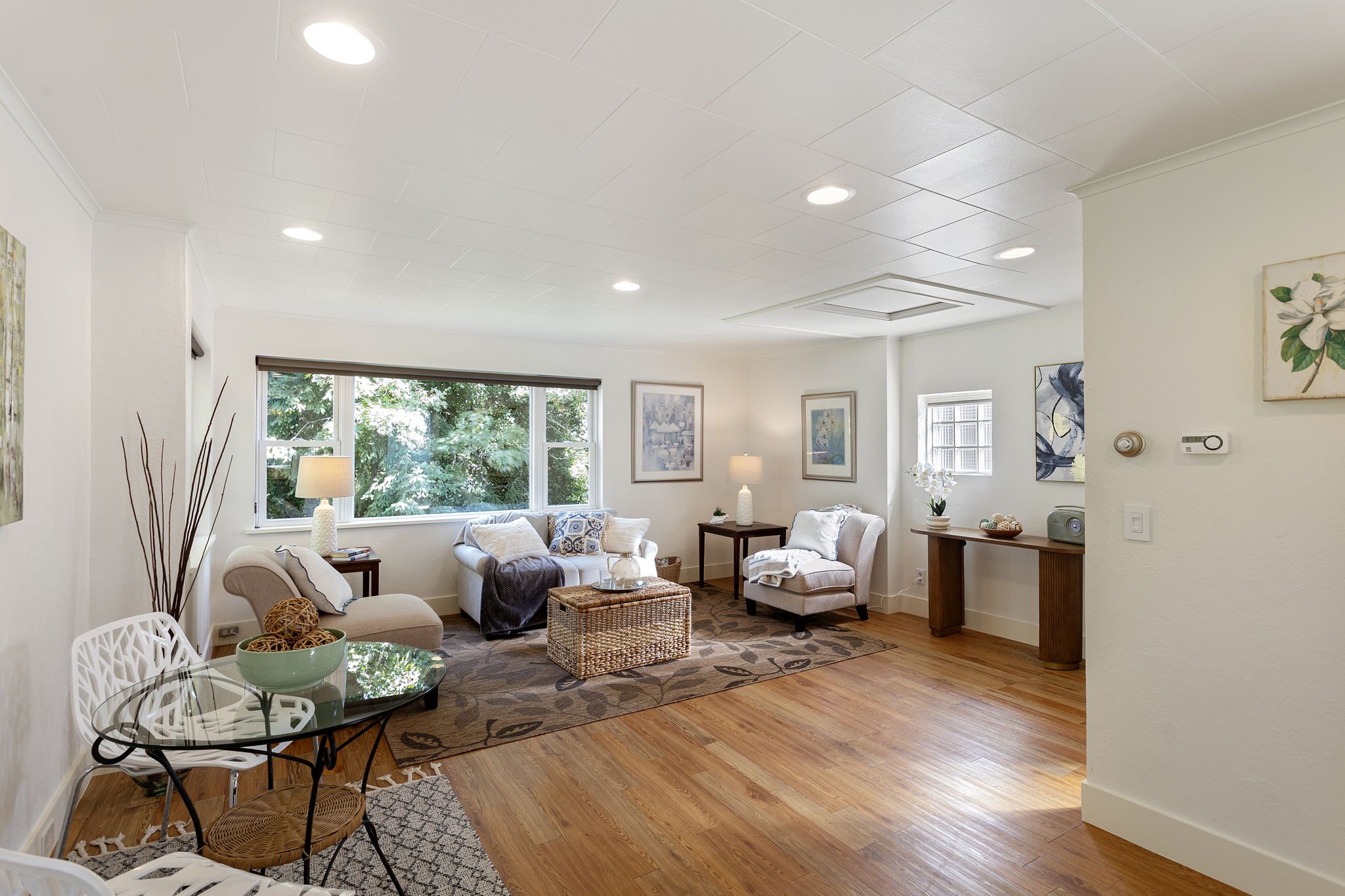 Framed by wide windows and a leafy backdrop, the living space feels gently elevated—tucked into the trees with quiet separation from the street.
