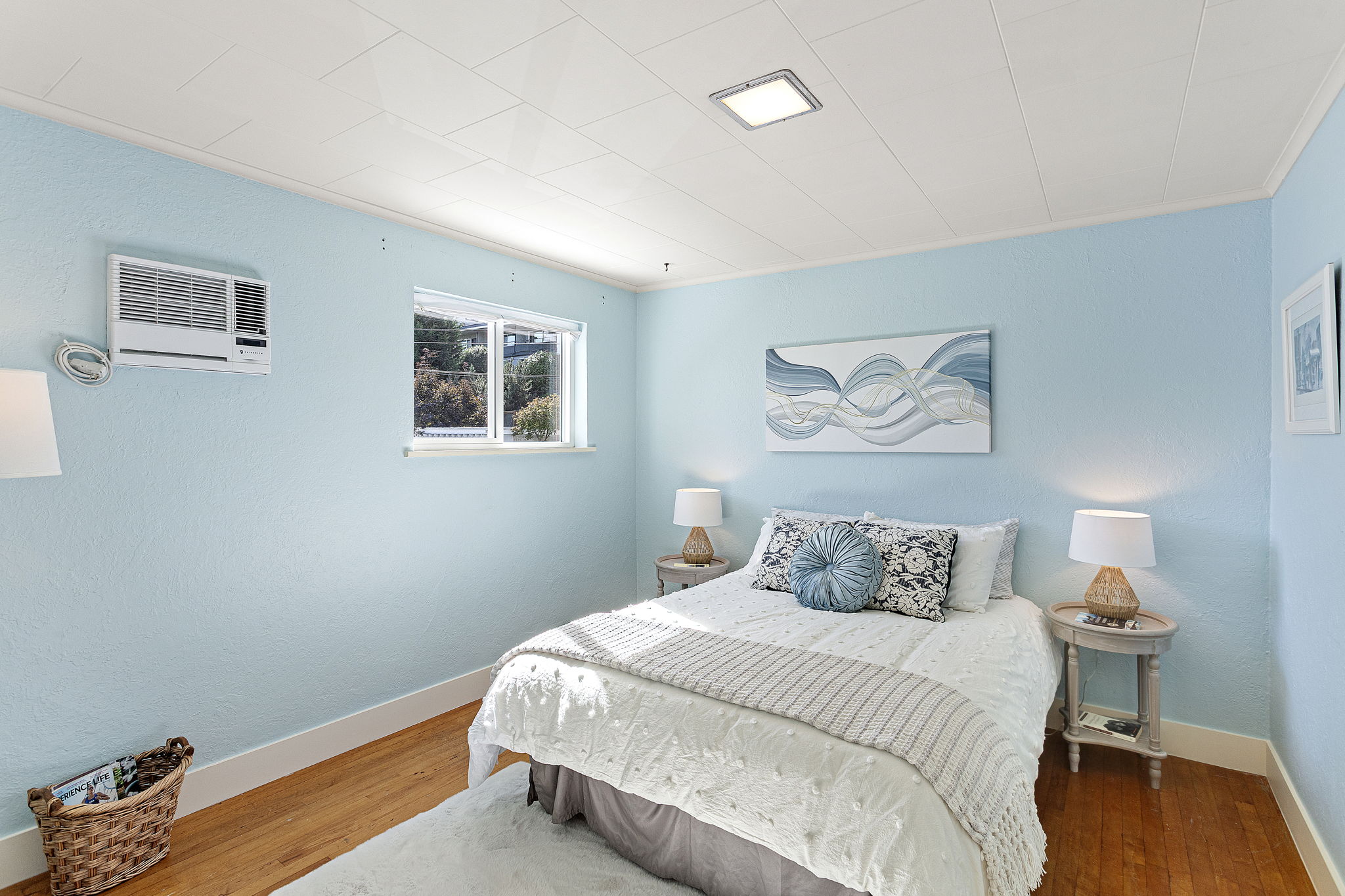 Peaceful bedroom with hardwood floors and a south-facing window for light throughout the day.