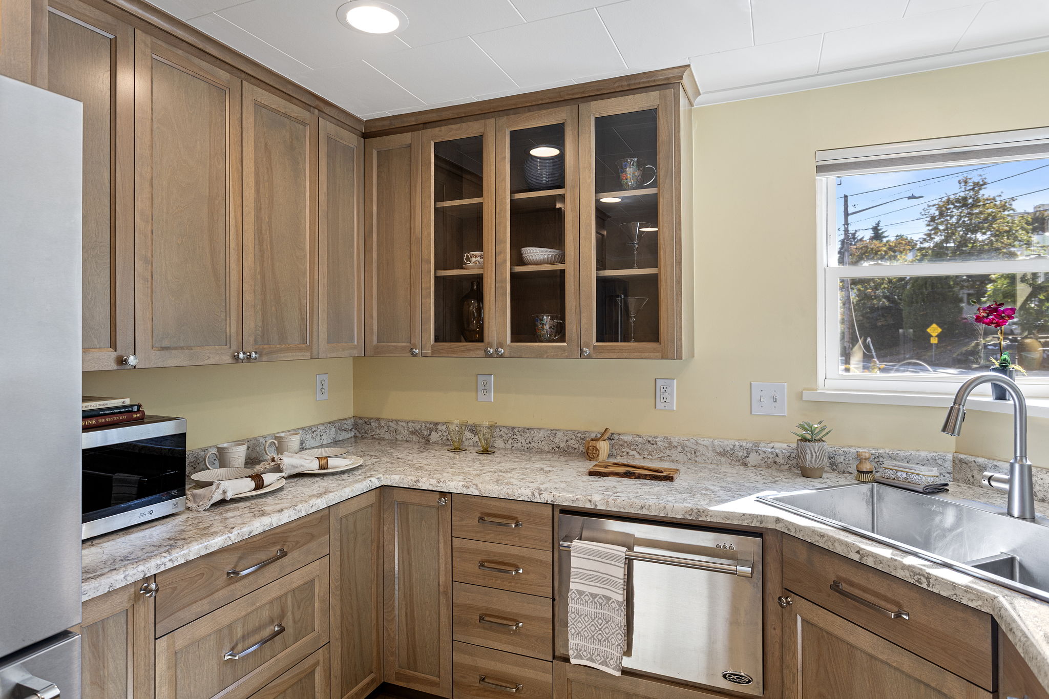 Granite-look Formica surfaces, tile floors, and glass-front cabinetry—durable finishes with subtle charm and plenty of space to work and store.
