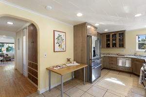 The refreshed kitchen opens into a bright living space—laminate flooring currently in place, with real hardwoods beneath ready for renewal.