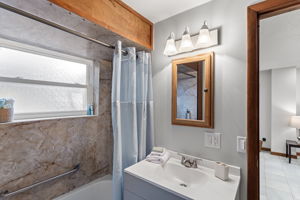 The full bathroom is updated with a modern vanity, soft lighting, and a large window for natural light—simple and clean, with timeless finishes.