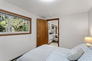 The cozy north bedroom features fresh carpet, ample closet space, and a peaceful view toward the private parking area.