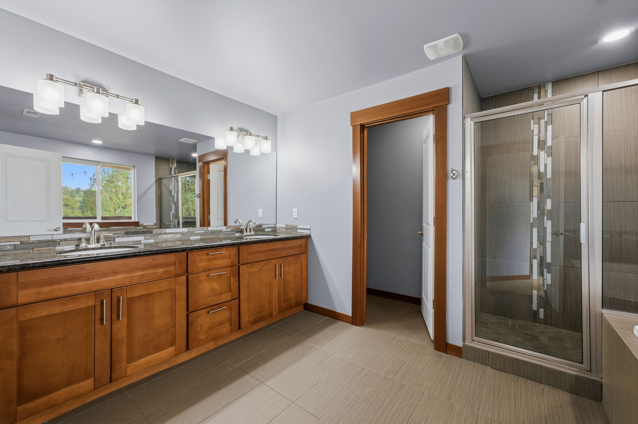 Upstairs primary bathroom, with tile flooring, mahogany cabinetry, quartz countertop, dual sinks, and separated toilet area