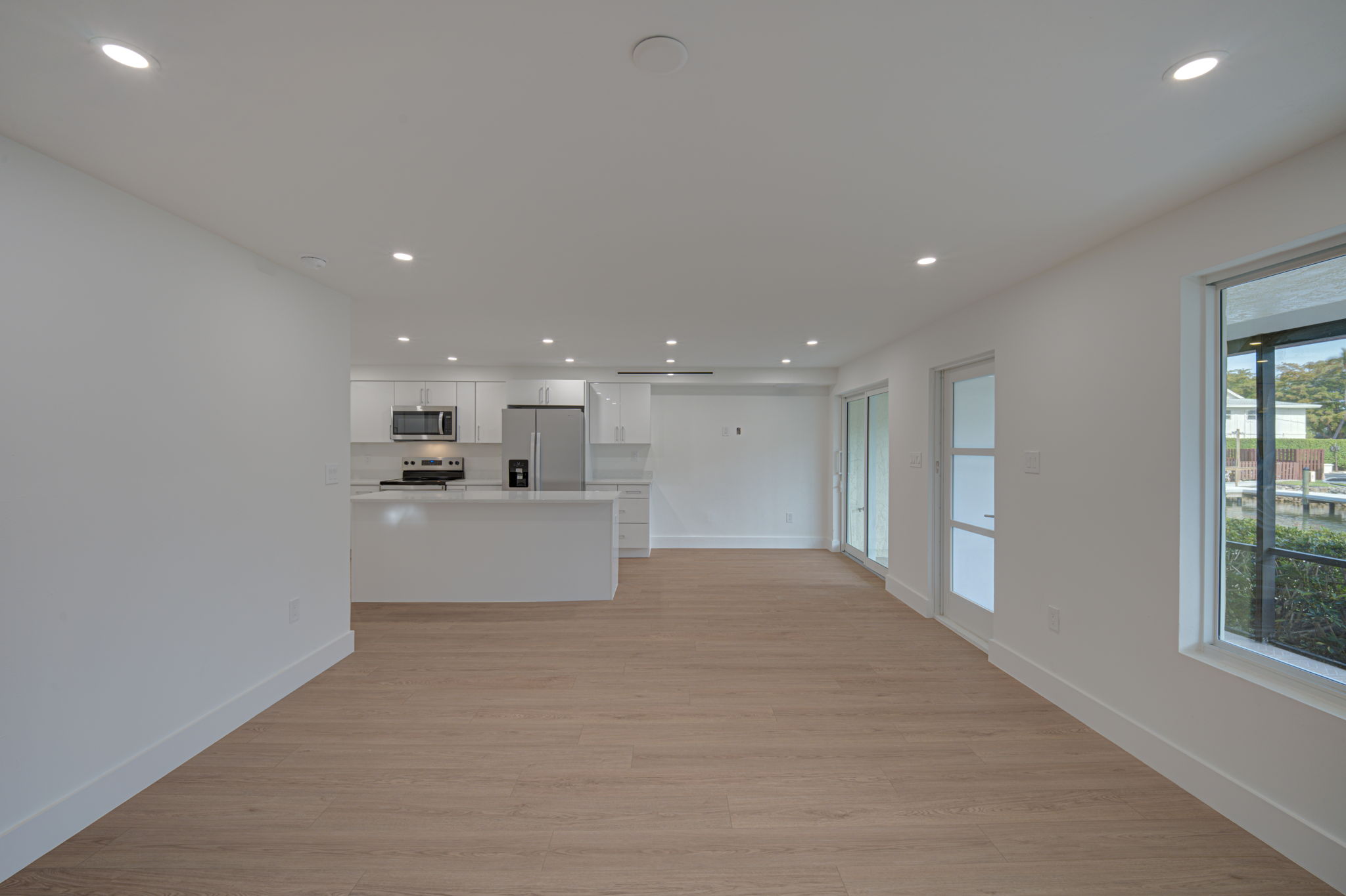 Expansive great room utilizing a coastal-modern aesthetic with continuous LVP flooring and wall-to-wall impact sliding glass doors for maximum natural light.