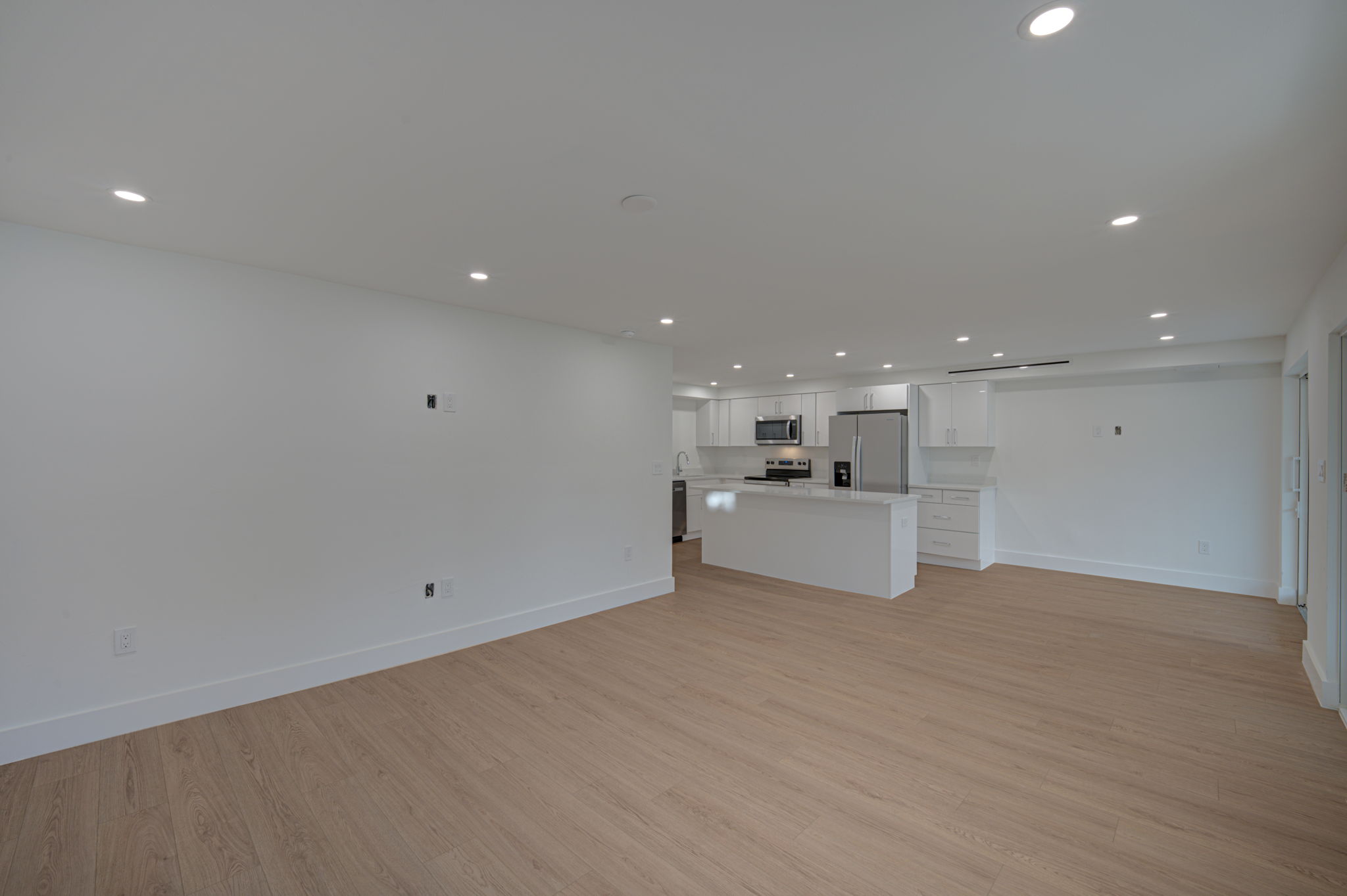 Wide-angle view of the kitchen and dining area emphasizing the structural open floor plan and large peninsula breakfast bar