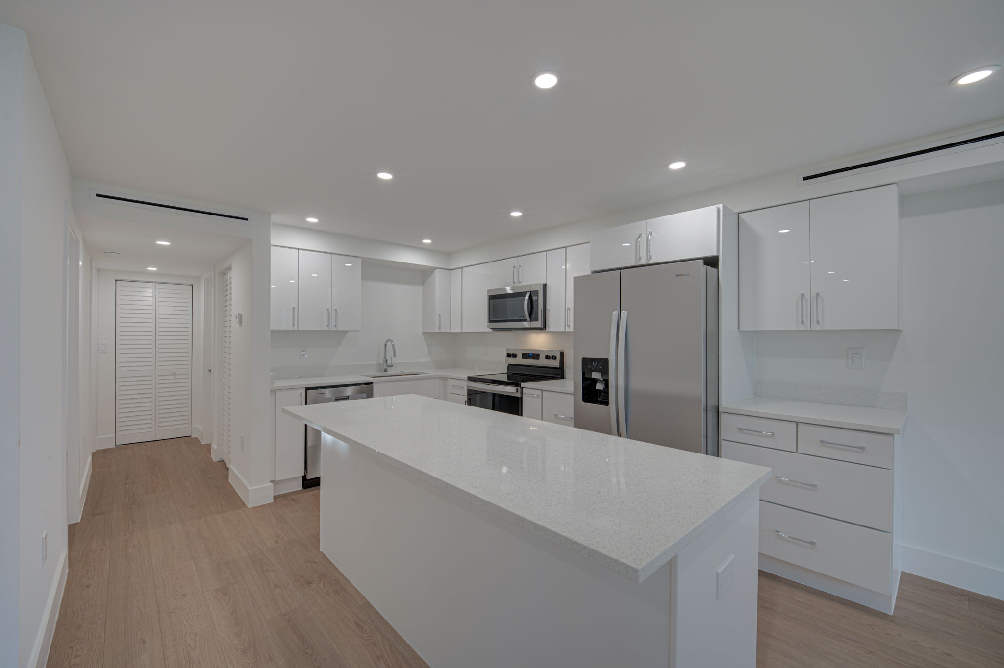 Detailed kitchen view showing high-end stainless steel appliances, modern geometric hardware, and a seamless quartz backsplash.