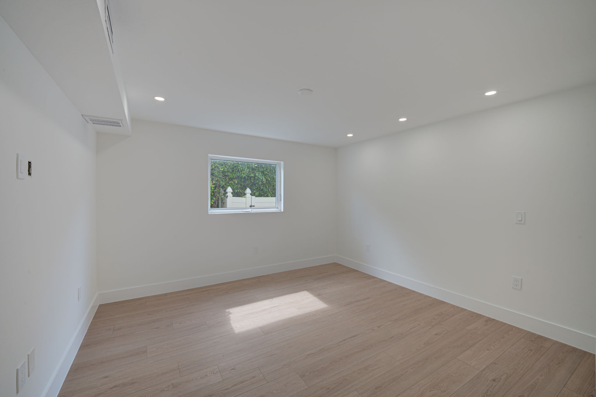 Guest bedroom providing ample natural light through dual impact-resistant windows, finished with baseboard molding and LVP flooring.