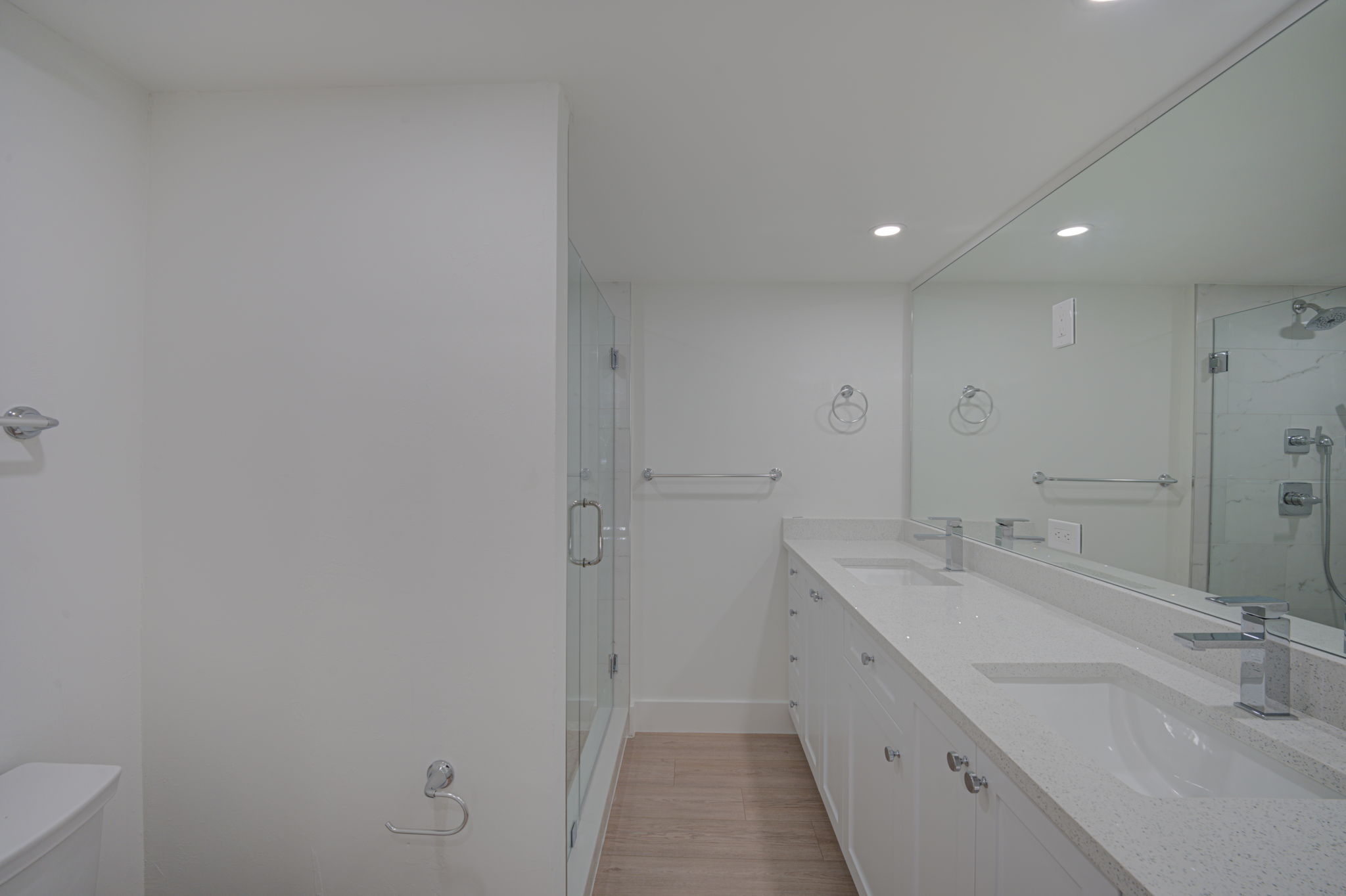 Modernized en-suite bathroom showcasing a frameless glass walk-in shower enclosure with custom floor-to-ceiling tile work.