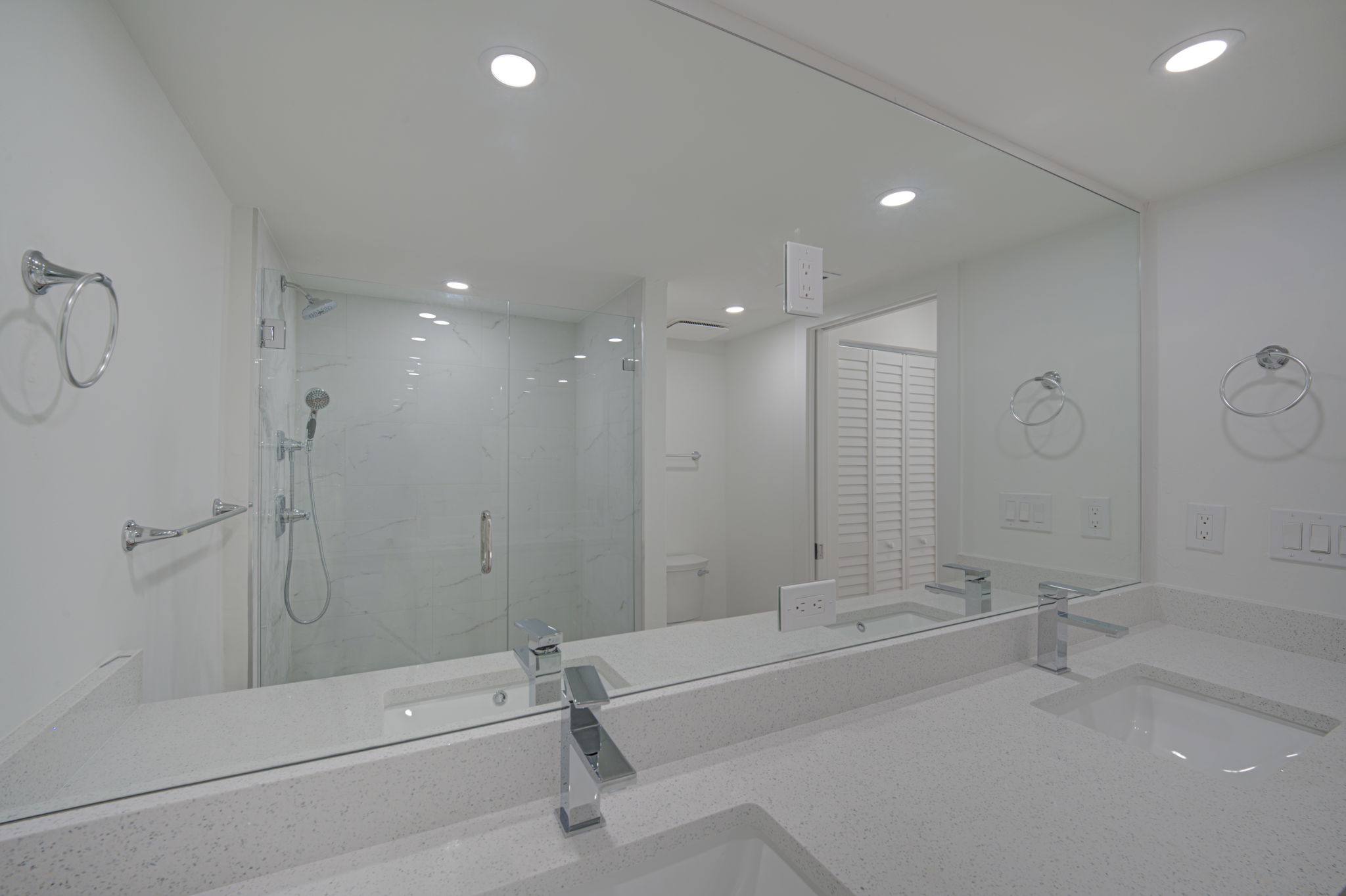 Upgraded bathroom vanity area featuring a double-sink quartz countertop, shaker cabinetry, and an oversized framed mirror